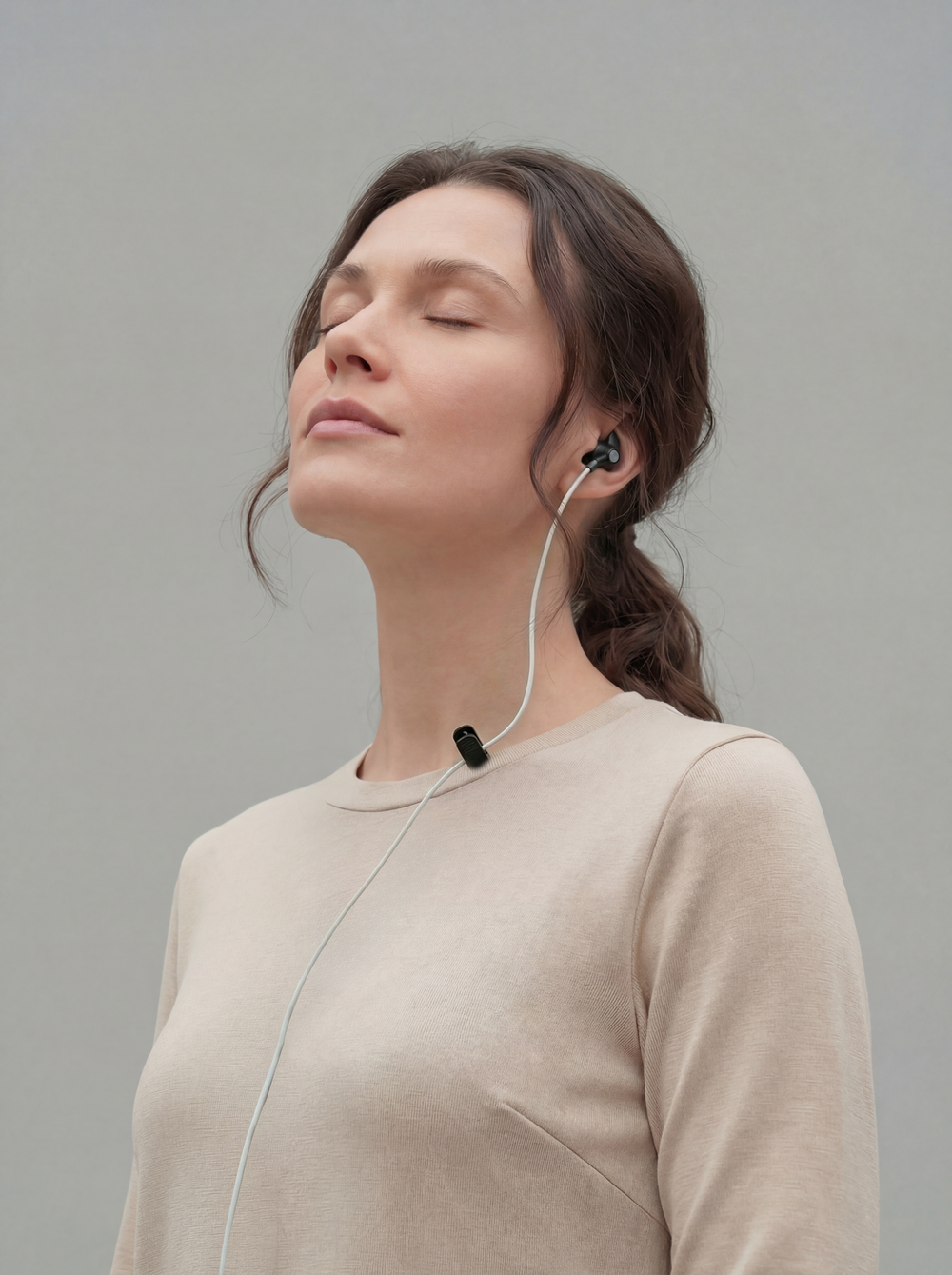Woman using ZenoWell ear device for stress relief and relaxation, benefiting from vagus nerve stimulation (taVNS) to enhance calm and promote well-being.